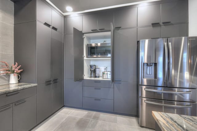 kitchen featuring stainless steel appliances, light stone countertops, tile walls, and light tile patterned floors