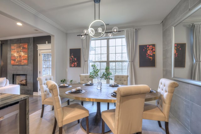 dining area with crown molding, a large fireplace, a chandelier, and hardwood / wood-style floors