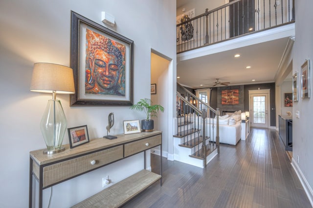 interior space featuring ceiling fan, a high ceiling, a fireplace, wood-type flooring, and ornamental molding