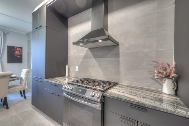 kitchen featuring stainless steel gas stove, backsplash, exhaust hood, and dark stone counters