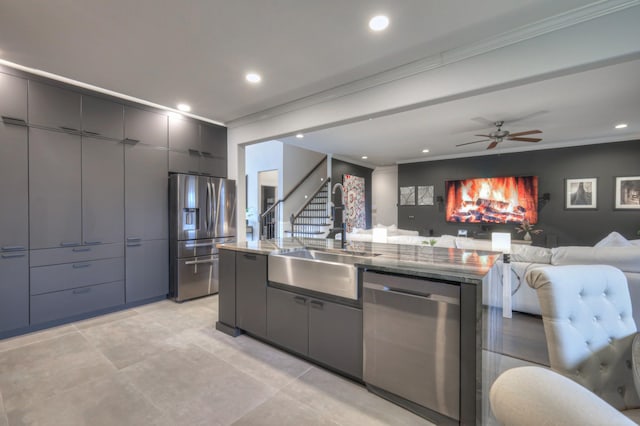 kitchen with stainless steel appliances, crown molding, sink, and a center island with sink