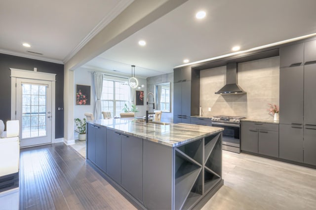 kitchen featuring sink, a kitchen island with sink, light stone countertops, stainless steel range oven, and wall chimney exhaust hood