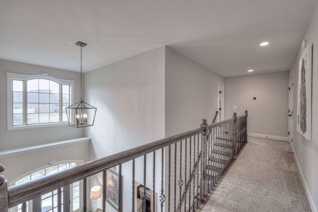 hallway featuring carpet flooring and a chandelier