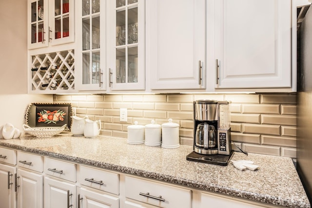 kitchen with decorative backsplash, light stone counters, and white cabinetry