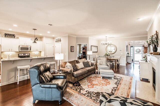 living room featuring a notable chandelier, crown molding, a premium fireplace, and dark wood-type flooring