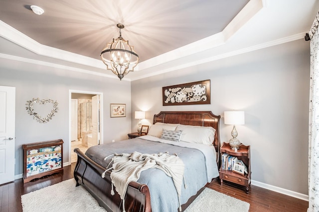 bedroom with a notable chandelier, dark hardwood / wood-style floors, a raised ceiling, and connected bathroom