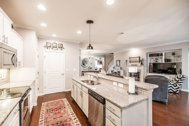 kitchen featuring white cabinetry, light stone countertops, hanging light fixtures, stainless steel appliances, and a kitchen island with sink