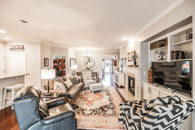 living room featuring light hardwood / wood-style floors, a high end fireplace, a chandelier, and ornamental molding