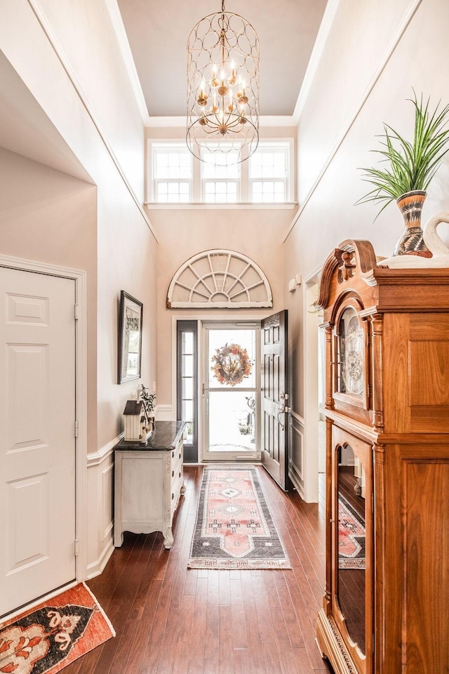 entryway featuring dark hardwood / wood-style flooring, a towering ceiling, and a notable chandelier