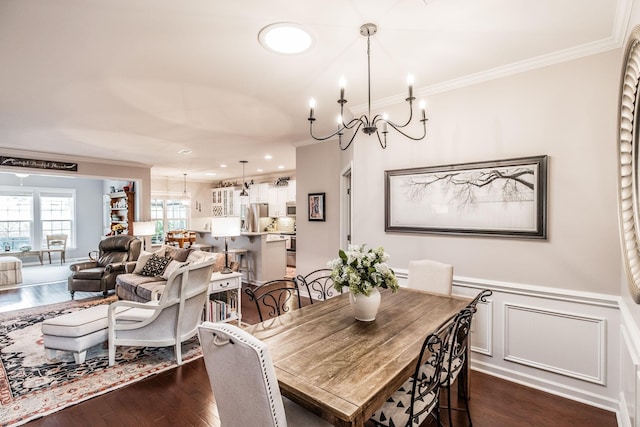 dining area featuring dark hardwood / wood-style flooring, ornamental molding, and a notable chandelier