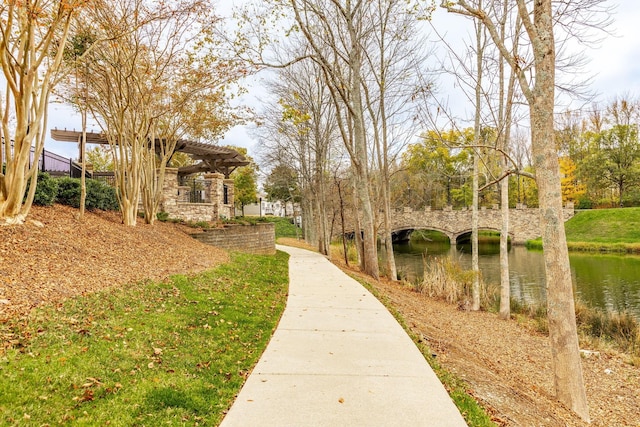 view of home's community with a water view and a pergola