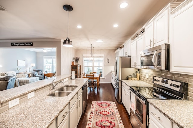 kitchen featuring light stone countertops, appliances with stainless steel finishes, decorative backsplash, pendant lighting, and white cabinetry