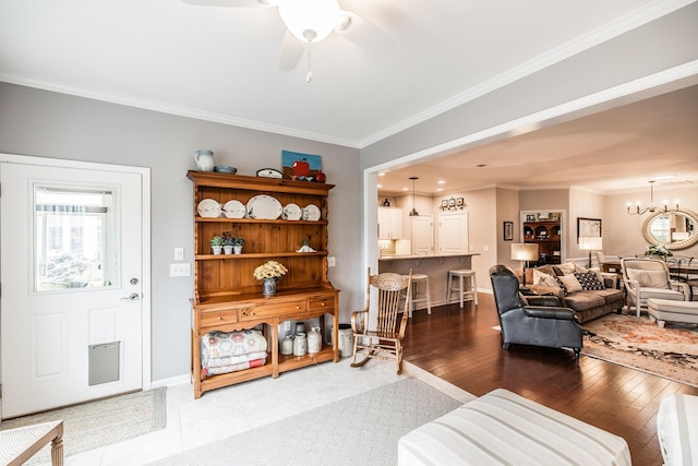 living room with ceiling fan with notable chandelier, light hardwood / wood-style flooring, and crown molding