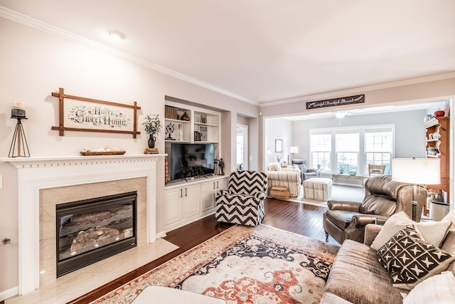 living room featuring built in shelves, hardwood / wood-style flooring, crown molding, and a premium fireplace