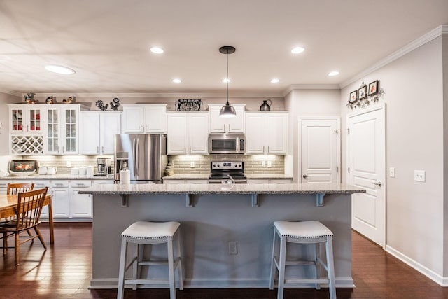 kitchen with dark hardwood / wood-style flooring, white cabinetry, a kitchen island with sink, and appliances with stainless steel finishes