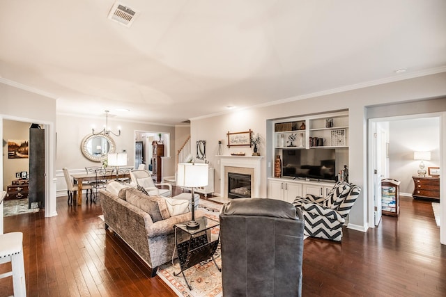 living room featuring built in features, ornamental molding, dark hardwood / wood-style floors, and a notable chandelier