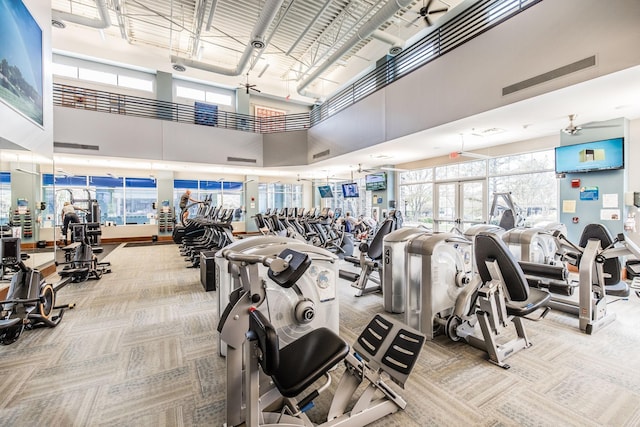 workout area featuring light carpet, a high ceiling, and ceiling fan