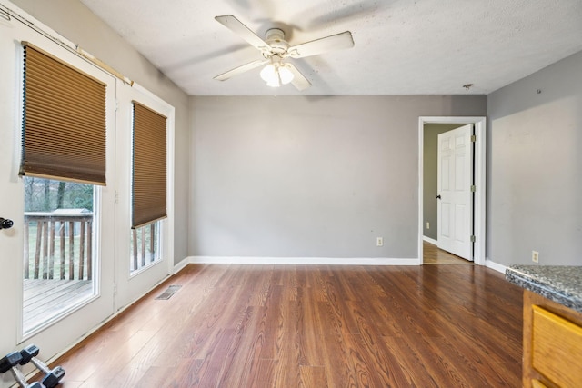 unfurnished room with a textured ceiling, dark hardwood / wood-style floors, and ceiling fan