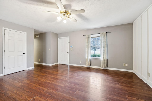 spare room featuring ceiling fan, dark wood-type flooring, and a textured ceiling