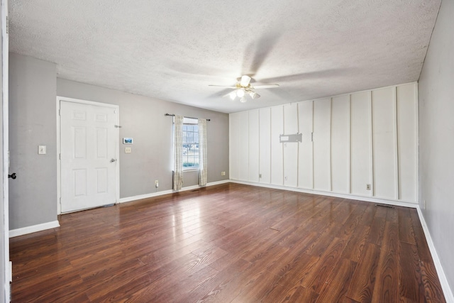 empty room with a textured ceiling, dark hardwood / wood-style floors, and ceiling fan