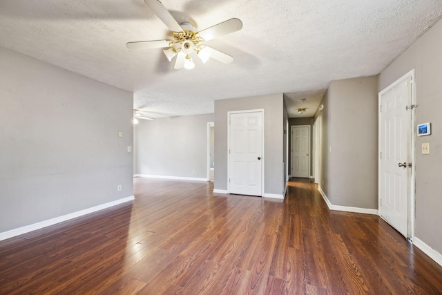 empty room with ceiling fan, dark wood-type flooring, and a textured ceiling