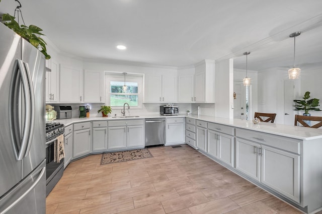 kitchen featuring kitchen peninsula, decorative backsplash, stainless steel appliances, sink, and decorative light fixtures