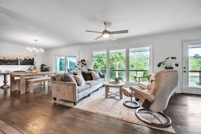 living room featuring ceiling fan with notable chandelier, ornamental molding, and dark wood-type flooring