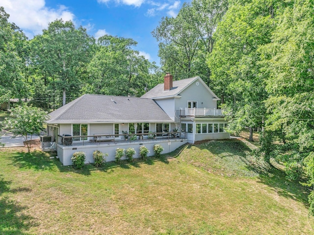 rear view of property featuring a lawn and a balcony