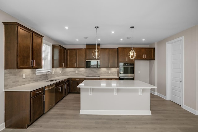 kitchen with light wood-type flooring, a kitchen island, hanging light fixtures, and black appliances