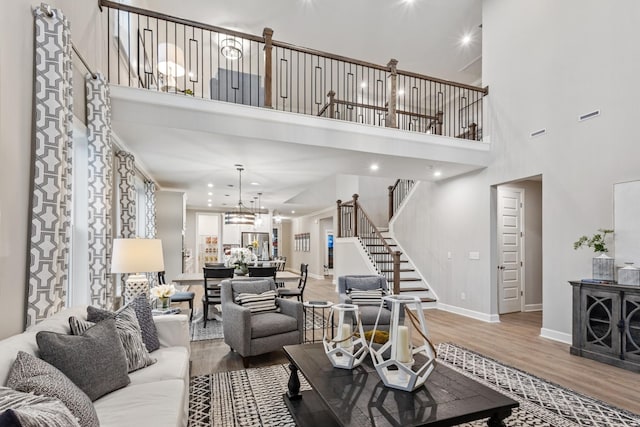 living room with a high ceiling, a notable chandelier, and hardwood / wood-style floors