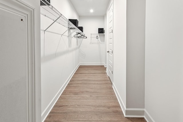 walk in closet with light hardwood / wood-style flooring