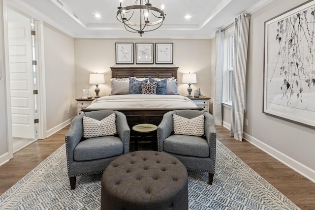 bedroom featuring hardwood / wood-style floors, a raised ceiling, crown molding, and a chandelier