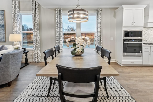 dining area with light hardwood / wood-style floors, an inviting chandelier, and crown molding