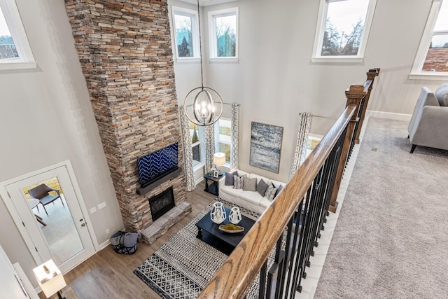 living room featuring a fireplace, a chandelier, a high ceiling, and hardwood / wood-style flooring