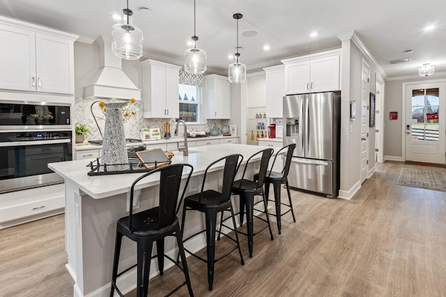 kitchen featuring white cabinets, pendant lighting, premium range hood, and stainless steel appliances