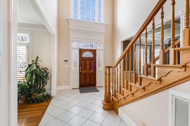 tiled entryway featuring a high ceiling and crown molding