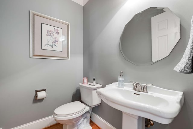 bathroom with wood-type flooring, toilet, and sink