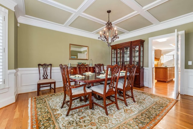 dining room with ornamental molding, a chandelier, light hardwood / wood-style flooring, and coffered ceiling