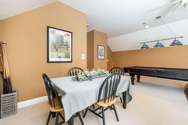 dining space with vaulted ceiling and light colored carpet