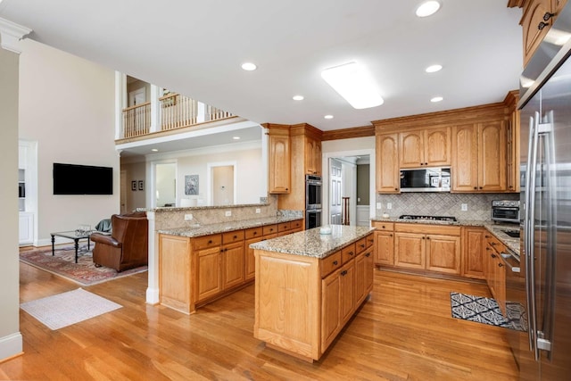 kitchen with kitchen peninsula, a center island, light hardwood / wood-style floors, decorative backsplash, and appliances with stainless steel finishes