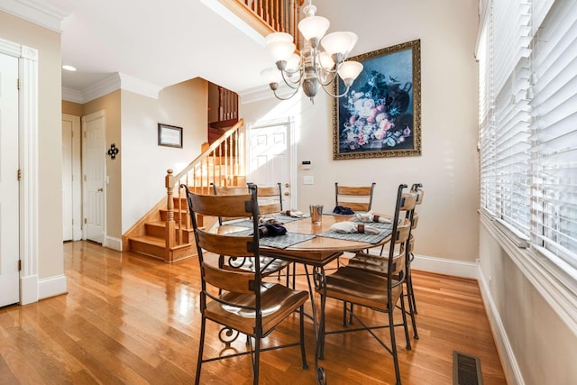 dining space featuring crown molding, a chandelier, and hardwood / wood-style floors