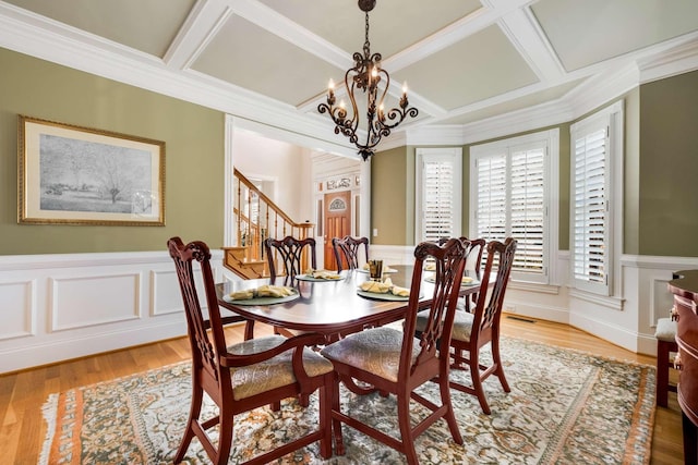 dining space featuring a notable chandelier, light hardwood / wood-style floors, coffered ceiling, and ornamental molding