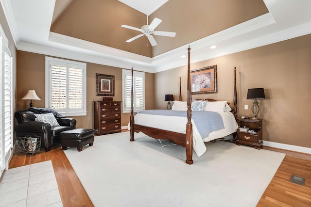 bedroom with hardwood / wood-style flooring, crown molding, and a tray ceiling