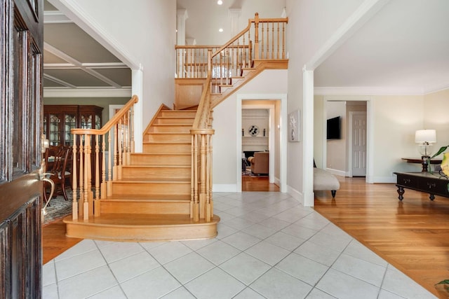 stairs featuring a high ceiling, ornamental molding, and tile patterned floors