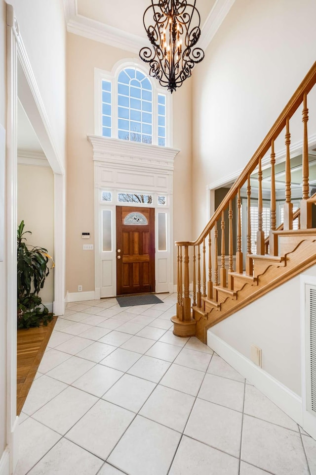 tiled entrance foyer with an inviting chandelier, crown molding, and a high ceiling