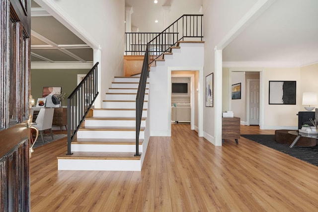 entrance foyer with ornamental molding, a high ceiling, and light wood-type flooring