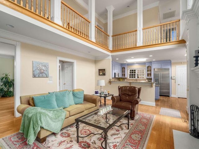 living room with ornamental molding, light hardwood / wood-style floors, and a high ceiling