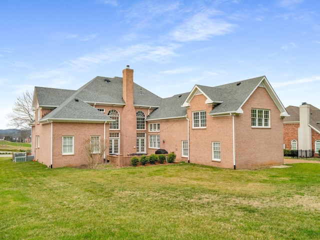 rear view of house featuring central AC unit and a yard