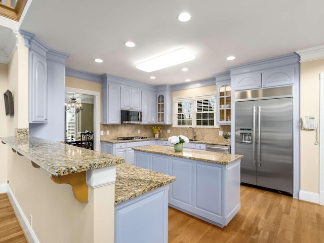 kitchen with a center island, appliances with stainless steel finishes, kitchen peninsula, light hardwood / wood-style floors, and decorative backsplash