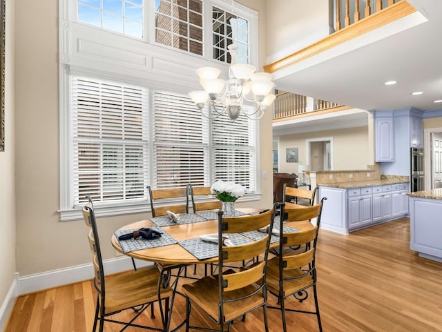 dining space featuring a chandelier, light hardwood / wood-style floors, and a high ceiling